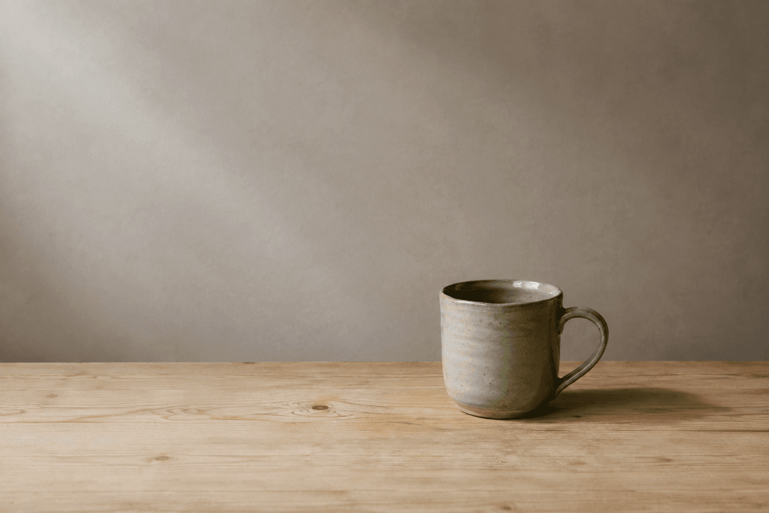 The same green mug in a wider wooden tabletop composition.