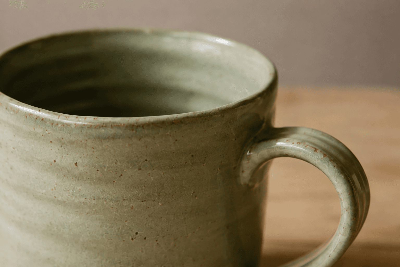 A close view of the green mug rim, glaze and handle joint.